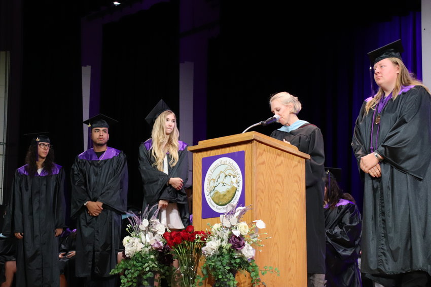 Students stand on stage as a staff member speaks at the Colorado's Finest High School of Choice graduation ceremony. Teachers recounted memories of their students and shared praise for them, one by one, before the students posed for photos with their diplomas.